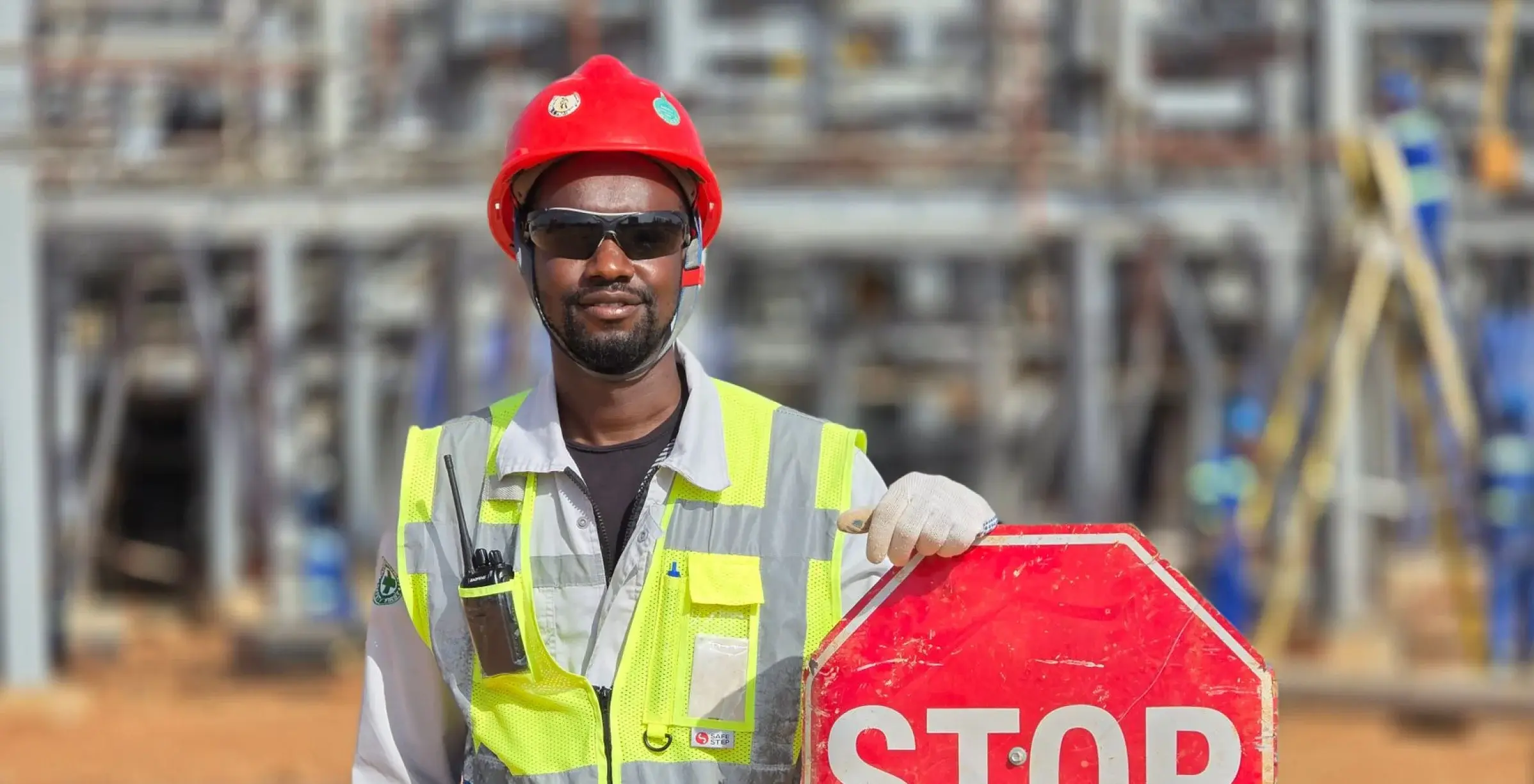 Xtetix site safety officer in full PPE holding a stop sign on a facility project